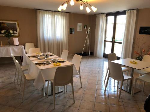uma sala de jantar com mesas e cadeiras brancas em Appartamenti Isola Verde em Villa
