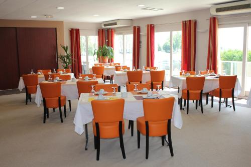 a conference room with white tables and orange chairs at Cit'Hotel Les Alizés in Limoges