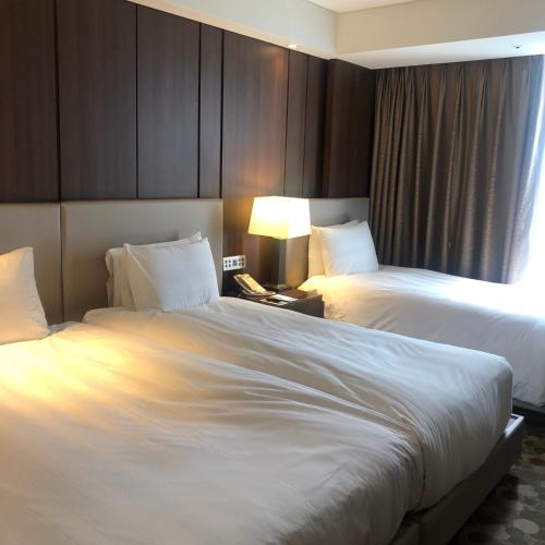 a hotel room with two beds and a lamp at LOTTE City Hotel Daejeon in Daejeon