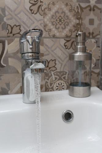 ein Waschbecken im Badezimmer, aus dessen Wasserhahn Wasser läuft in der Unterkunft Polychrono Suite 2 in Polychrono