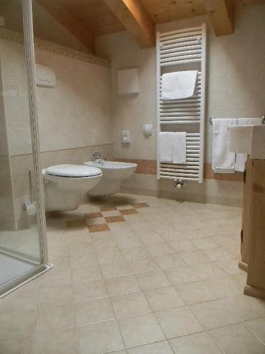 a bathroom with a toilet and a tub and a sink at Hotel Mountain Resort in Commezzadura