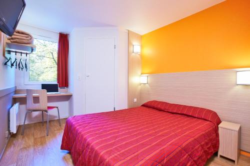 a hotel room with a red bed and a desk at Premiere Classe Geneve - Saint Genis Pouilly in Saint-Genis-Pouilly