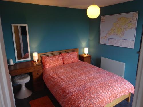 1 dormitorio con cama roja y pared azul en Little Trenoweth, en Saltash