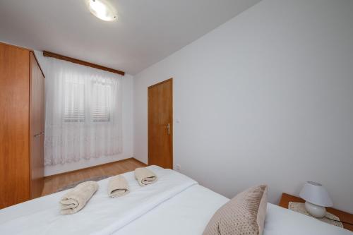 a white bedroom with two towels on a bed at Villa Milena in Trogir