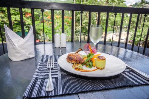 a plate of food on a table with a glass of wine at Viyana Boutique Hotel in Kandy