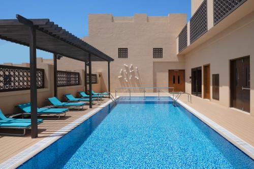 Hyatt Place Dubai Wasl District Residences في دبي: مسبح مع كراسي صالة ومسبح