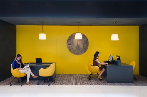 two women sitting in yellow chairs in a yellow wall at Hyatt Place Dubai Wasl District Residences in Dubai