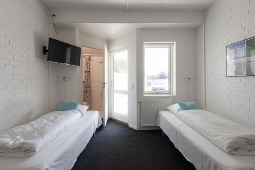 2 witte bedden in een kamer met een raam bij Motel Poppelvej in Herning