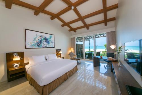 - une chambre avec un grand lit blanc et un bureau dans l'établissement Danat Jebel Dhanna Resort, à Jebel Dhanna