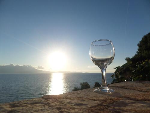 a glass of wine sitting on a rock near the water at Endless Blue in Ravdhoúkha