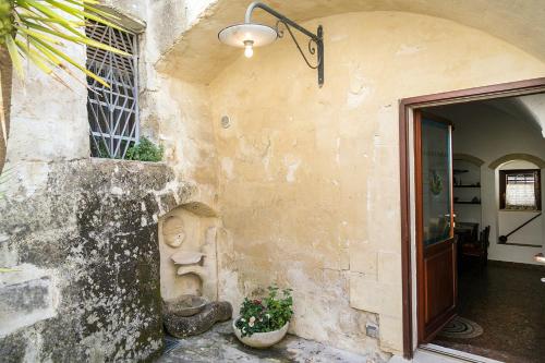 a stone building with a door and two potted plants at Umbra Idris Holiday Home in Matera