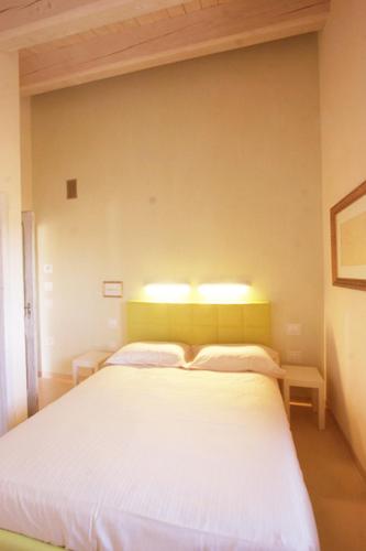 a bedroom with a white bed with two pillows at Agriturismo Pozzuolo in Serrungarina