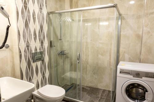 uma casa de banho com um chuveiro e uma máquina de lavar roupa em Vip Apart Hotel em Bursa