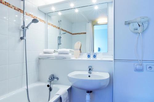 een witte badkamer met een wastafel en een douche bij Kyriad Genève St-Genis-Pouilly in Saint-Genis-Pouilly