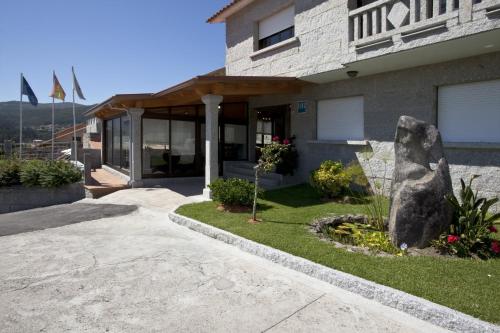 a house with a rock in the front yard at Hotel Liñares in Poio
