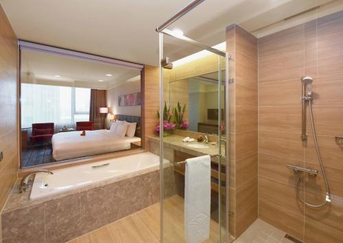 a bathroom with a bath tub and a bedroom at Fullon Hotel Taoyuan Airport Access MRT A8 in Guishan