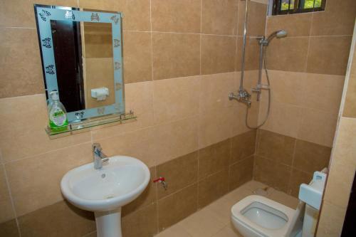 une salle de bain avec un lavabo, des toilettes et un miroir dans l'établissement Mikocheni Condo Hotel & Apartments, à Dar es Salaam