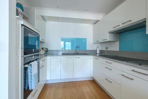uma cozinha com armários brancos e um lavatório em The Point em Exmouth