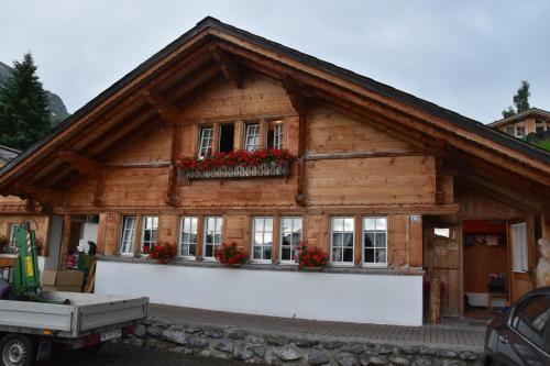 a wooden house with flowers in the windows at Chemihüttli Apartments Axalp in Axalp