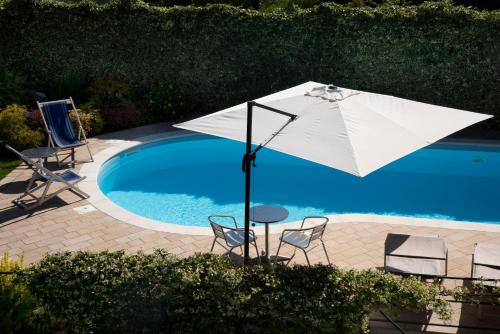 an umbrella and chairs next to a swimming pool at Cascina36 B&B in Pregnana Milanese