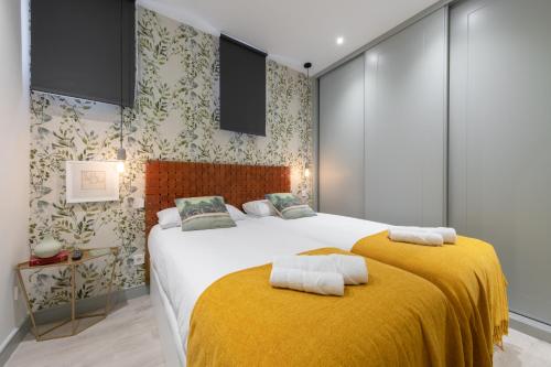 een slaapkamer met een groot bed en een gele deken bij Sophisticated brand new flat in Madrid