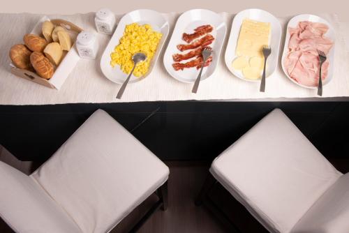 a table with plates of food and two white chairs at Cascina36 B&B in Pregnana Milanese