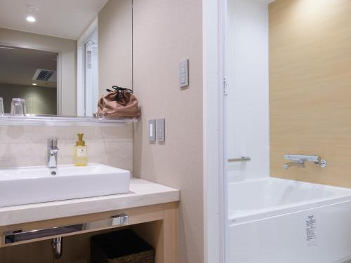 a white bathroom with a sink and a mirror at Nara Royal Hotel in Nara