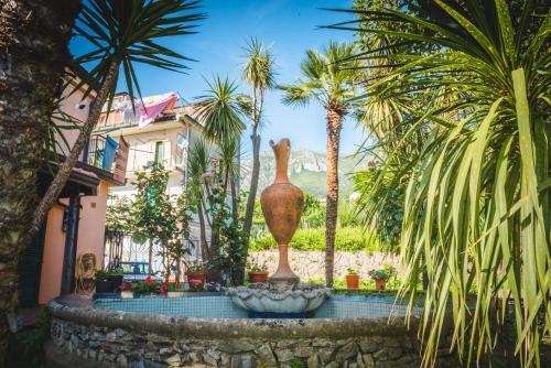 a fountain in a courtyard with palm trees and a house at Belvedere di Gloria in Tramonti