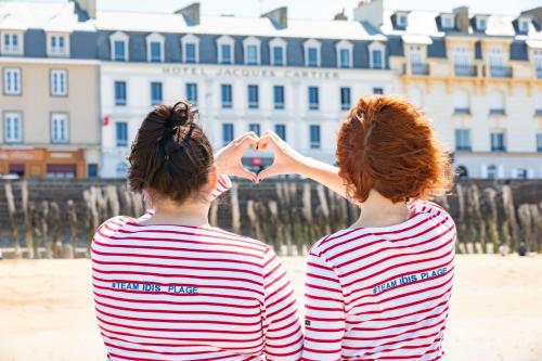 Dos mujeres haciendo un signo de corazón en la playa en ibis Saint Malo Plage, en Saint-Malo