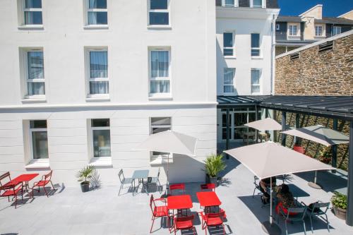an outdoor patio with chairs and tables and umbrellas at ibis Saint Malo Plage in Saint Malo