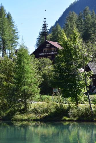 a house sitting on top of a hill next to a lake at Hotel - Restaurant - Sonnblick in Heiligenblut