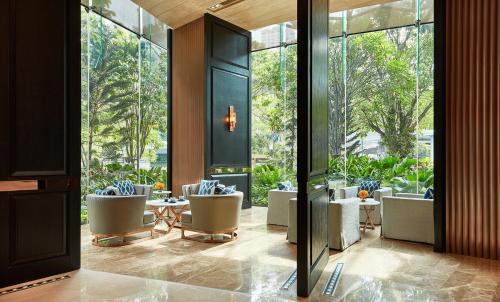 a lobby with chairs and a table and windows at Hyatt Regency Bangkok Sukhumvit in Bangkok