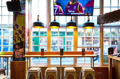 a restaurant with a bar with stools in front of a window at St Christopher's Inn Bath in Bath