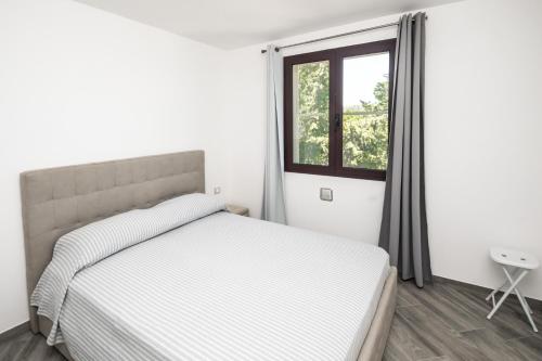 a white bedroom with a bed and a window at Sa lampana in Orosei