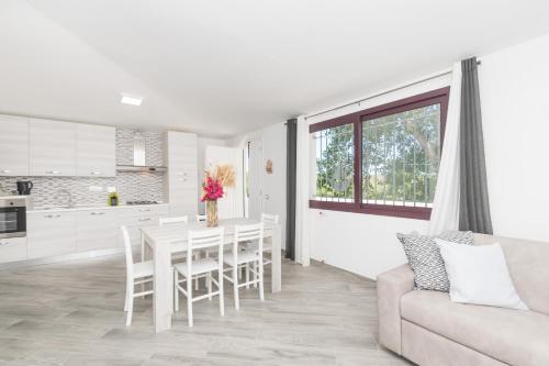 a white kitchen and dining room with a table and a couch at Sa lampana in Orosei