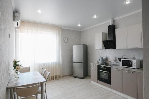 a kitchen with a table and a stainless steel refrigerator at Двухкомнатная квартира рядом с ТРК Красная площадь in Krasnodar