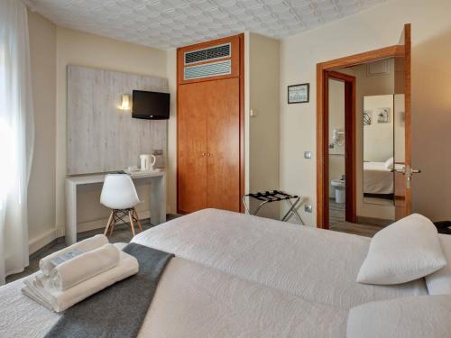 a bedroom with a large white bed and a bathroom at Hotel Los Angeles in Figueres