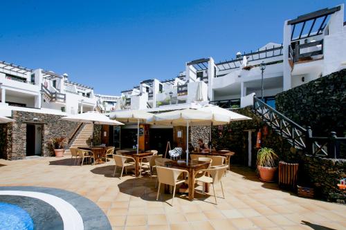a patio with tables and umbrellas in front of a building at Club Oceano in Puerto del Carmen
