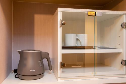 a glass cabinet with a coffee maker in it at Hotel Wing International Asahikawa Ekimae in Asahikawa