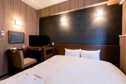 a bedroom with a bed and a desk and a television at Hotel Wing International Asahikawa Ekimae in Asahikawa