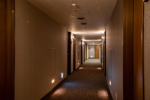 an empty hallway with a long corridor with lights at Hotel Wing International Asahikawa Ekimae in Asahikawa