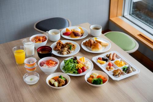 a table with many plates of food on it at Hotel Wing International Asahikawa Ekimae in Asahikawa
