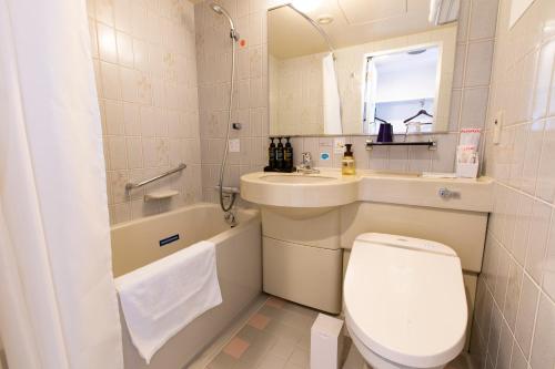 a white bathroom with a toilet and a sink at Hotel Wing International Asahikawa Ekimae in Asahikawa