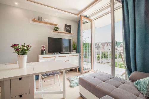 a living room with a desk and a large window at Apartament słoneczny in Polanica-Zdrój