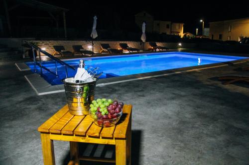 a bowl of fruit on a table next to a pool at Merita Apartments with Pool in Sveti Filip i Jakov