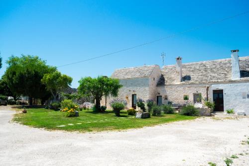 uma antiga casa de pedra com um jardim de relva em B&B Trulli Donna Isabella em Locorotondo