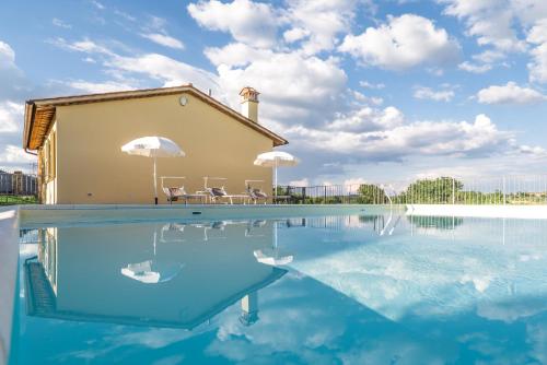 une piscine avec deux chaises et une maison dans l'établissement Le Case Di Camin Bianco, à Castelfiorentino