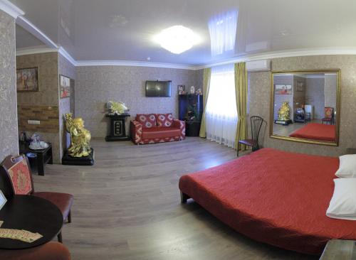 a bedroom with a red bed and a couch at Міні-готель Пекін in Mykolaiv