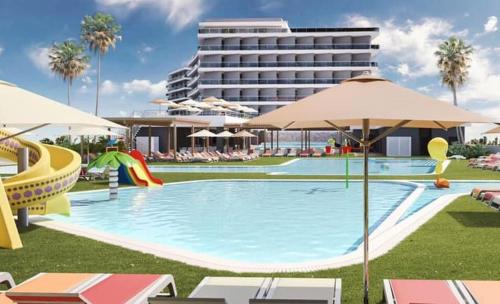 a swimming pool with chairs and umbrellas next to a hotel at AZ Hôtels Zephyr in Mostaganem