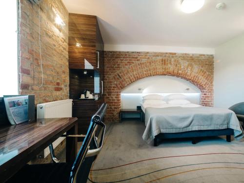 a bedroom with a bed and a brick wall at Q Hotel Grand Cru Gdańsk in Gdańsk